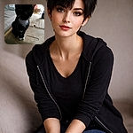 A curious tuxedo kitten leans toward the camera, whiskers forward and tiny white paws perched on a dusty plastic crate — part inquisitive model, part snack inspector, fully unimpressed by your phone skills.