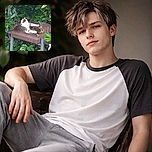 A fluffy cat lounges comfortably on a rusty old grill surrounded by lush green foliage, looking like the king of this secret garden hideout.