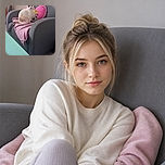 A very serious-looking cat sits proudly on a gray armchair, as if guarding the pink blanket and cartoon pillow from imaginary household intruders. The turquoise coffee table adds a splash of color while the radiator quietly supervises from behind.