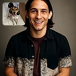 A happy, attentive dog with big floppy ears and a spotted coat stands on a tiled floor looking up with bright, eager eyes and a wide smile, as if ready for a game or a treat.