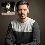 A poised gray and white cat sits elegantly on the edge of a carpeted floor, staring intently at the camera with bright yellow eyes. The background features a wooden floor and dark furniture, making the cat the undeniable star of the scene.