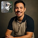 A happy dog looks up with a goofy grin, sitting on a patchy grassy area next to a dirt path, while the photographer's feet peek into the frame, making it feel like a candid moment between pals.