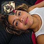A delightfully upside-down dog is giving the camera its best wrinkly grin, showing off a giant nose, bright eyes, and tiny teeth while lounging dramatically on a blanket like a canine comedian between punchlines.