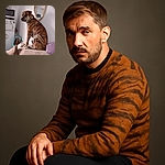 A handsome brindle dog sits majestically on a cozy couch, casting a sideways glance as if pondering the mysteries of the universe. The room is softly lit, with a mirror reflecting part of the scene and a fridge adorned with magnets and notes adding a homey touch.