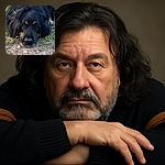 A close-up photo of a large black and brown dog lying down on a patch of grass and dirt, looking directly at the camera with soulful eyes, capturing a peaceful and contemplative moment.