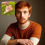 A fluffy orange and white cat lounges gracefully on a lush green lawn, with a soft-focus background featuring vibrant pink flowers and a path, capturing a serene and charming outdoor moment.