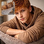 A cozy orange tabby cat is lounging comfortably in a soft, elevated hammock on a multi-level cat tree, looking relaxed and slightly sleepy with a calm expression.