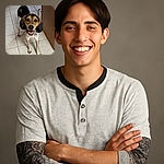 A happy, attentive dog with big floppy ears and a spotted coat stands on a tiled floor looking up with bright, eager eyes and a wide smile, as if ready for a game or a treat.
