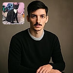 A sleek black and white tuxedo cat sits regally on a cozy bed surrounded by colorful plush toys, including a large blue Stitch character, against a soft pink wall, giving off an air of calm curiosity.