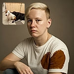 Two adorable dogs chilling in a cozy kitchen; one white with brown patches sitting upright while the black dog lounges nearby, both sharing a calm and friendly moment on the tiled floor.