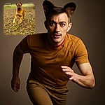 An energetic dog dashes joyfully through a leaf-covered yard with ears flapping like little wings, set against a rustic backdrop of houses and bare trees on a cool day.