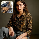 A curious tabby cat lounges on a gray fabric surface with a slightly disheveled look, surrounded by computer peripherals in the softly lit background, giving off a vibe of relaxed tech-savvy feline.