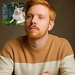 A fluffy cream and white cat lounges regally on a metal shelf surrounded by vibrant green leaves, gazing upward with a serene and contemplative expression, as if pondering the mysteries of the garden.