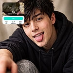 Bug the fluffy black Pomeranian leans into the camera with a dramatic tongue-lick while a giant voting app UI photobombs the shot — cozy indoor background, slightly soft/blurry focus, but overflowing with charm and personality.