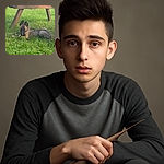 A playful puppy lies on lush green grass under a wooden bench, chewing on a stick with curious eyes and perky ears, enjoying a peaceful moment in the outdoors.