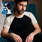 A cozy black and white cat is peacefully napping on a textured blue blanket, looking like the ultimate expert in relaxation with its eyes closed and body sprawled out comfortably.