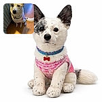 A big-eared, spotted dog gives a soulful puppy-eyed stare while wearing a colorful bandana, perched beside a striped bedspread on a warm wooden floor — looks ready to negotiate extra treats with utter sincerity.