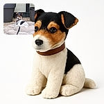 A small dog with a brown and black face and white body lounges on a fluffy beige blanket outdoors, flanked by two large black plant pots on a stone patio, looking curiously at the camera with ears perked up.