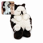 A fluffy black-and-white cat is sprawled across the bed like a tiny tuxedoed acrobat, apparently practicing an advanced upside-down cuddle pose while the patterned pillow looks on approvingly.