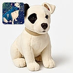A charming white dog with a black patch over one eye sits attentively on a grassy patch dotted with small white flowers, basking in the sunlight with a curious and gentle expression.