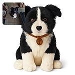 A fluffy black and white dog sits patiently on a tiled floor in a cozy, lived-in room filled with furniture and pet accessories, looking up with bright, curious eyes.