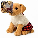 A slightly blurry photo of a dog wearing a cozy white sweater and a red plaid skirt, sitting on a plush blanket-covered couch, giving a side-eye glance that screams 'Why the outfit, human?'