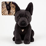 A sleek black dog sits attentively on a uniquely patterned floor, with large alert ears and soulful eyes, surrounded by homey furniture and a cozy bed in the background.