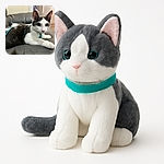 A curious black and white kitten lounges on a gray leather couch, wearing a bright teal harness and leash, with wide eyes full of wonder and a soft focus on its fluffy fur.