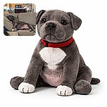 A large gray dog is sprawled out comfortably on a beige couch, using a cushion as a pillow and looking completely relaxed in a cozy living room setting with a kitchen in the background.