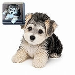 A fluffy little puppy lounges in a doorway like a shaggy security guard, one paw dramatically dangling over the threshold while its bright eyes announce that absolutely no one may enter without treats. A colorful sunburst doormat adds a cheerful welcome below.
