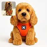 A charming golden dog wearing a bright orange harness with a butterfly emblem sits attentively on a tiled floor, looking up with big, soulful eyes and a slightly tilted head as if waiting for a treat or a command.