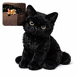 A sleek black cat lounges on a brown blanket, clutching a cute plush toy shaped like a bull with a red heart on its side, looking cozy and content.