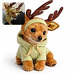 A tiny dog dressed as a festive reindeer with shiny antlers and a cozy green hoodie, perched on someone's lap looking adorably contemplative, ready to sleigh the holiday cuteness game.