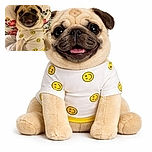 A happy pug dressed in a white shirt with yellow smiley faces lies on a floral pillow and white blanket, flashing a big grin that could brighten anyone's day.