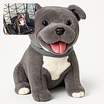 A happy, smiling dog lounges comfortably on a black cushioned swing chair indoors, with a modern white brick wall and wooden floor in the background. The dog's joyful expression and relaxed pose make it look like it's having the best day ever.