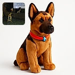 Three dogs wearing reflective harnesses pose on a dimly lit street at night. The photo is grainy and dark with their eyes glowing from the camera flash, giving them a spooky yet adorable look. They sit and stand near a brick wall with a partially visible sign in the background.