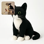 A curious tuxedo cat with bright green eyes perches proudly on a multi-level gray cat tree, striking a pose as if it owns the place. Behind the cat, a colorful artistic drawing of a cat adds a splash of vibrant contrast to the otherwise neutral-toned room.