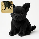 A cute black puppy with shiny fur sits attentively on a tiled floor, looking up with curious and soulful eyes, as if waiting for a treat or some belly rubs.