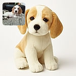 A sleepy beagle puppy lounges on a checkered blanket draped over a couch, with a soft-focus background featuring a flower arrangement and a cozy indoor setting.