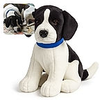 A black and white dog with a blue collar is lying down on a cartoon-printed blanket, seemingly sniffing or licking the fabric. The cozy indoor setting shows some yarn in the background, suggesting a crafty home environment.