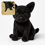 A cute black puppy with shiny fur sits attentively on a tiled floor, looking up with curious and soulful eyes, as if waiting for a treat or some belly rubs.