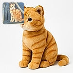 A charming orange tabby cat perched on a ledge, framed by some branches and leaves, looking off into the distance with a calm and curious expression. The soft focus and muted background highlight the cat's detailed fur pattern.