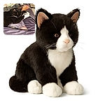 A cozy black and white cat is adorably snuggling up against a person's leg clad in zebra-patterned leggings. The scene is set on a bed with a blanket, and a cluttered nightstand holds Oreo cookies, a remote, and scissors, adding a casual, lived-in vibe.