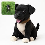 A joyful black and white dog is lying on a lush green lawn, happily panting with a tennis ball right in front of its paws and a leash trailing off to the side, ready for some playful fetch action.