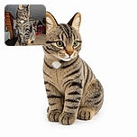 A serious tabby cat sits proudly on a table like the stern manager of the household, inspecting the room with bright green eyes while its whiskers conduct a full feline security scan.