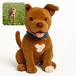 A lively brown dog with a white patch on its chest joyfully runs towards the camera across a sunlit grassy field, ears perked up and tail wagging, with a backdrop of urban buildings and a fence.