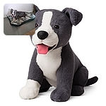 A happy dog lounges on a leafy patterned dog bed inside a room, tongue out and ears perked, looking ready for some belly rubs while the cozy carpet peeks in the foreground.