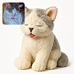 A fluffy white and grey cat is caught mid-lick with its tongue adorably sticking out, eyes closed in pure contentment, resting on a cozy mustard-colored cushion.