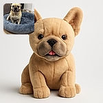 A charming French Bulldog sitting proudly in a fluffy gray dog bed, looking like the king of comfort with a slightly mischievous grin, surrounded by a cozy indoor setting with wooden flooring and a bit of wall wear.