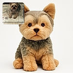 A small dog with fluffy ears and a cute face lies on a patterned mat on a wooden floor, looking directly at the camera with curious eyes, surrounded by household furniture and a wire basket in the background.